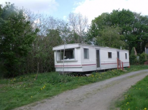 caravan nestled away amongst trees on edge of farm yard